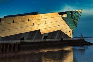 modern architectuur gebouw door de water Bij zonsondergang met dramatisch verlichting en reflecties. foto