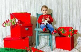 de weinig kind spelen met Kerstmis decoraties in studio, weinig kind met Kerstmis bal foto