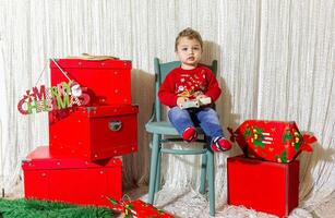 de weinig kind spelen met Kerstmis decoraties in studio, weinig kind met Kerstmis bal foto