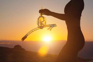 hand- houdt snorkelen stofbril tegen de achtergrond van de zonsondergang lucht. silhouet van een sexy vrouw Holding scuba uitrusting in haar handen foto