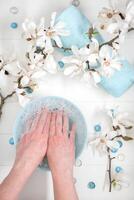 vrouw doorweekt haar handen in een kom met zeepachtig water en zee steentjes voor een delicaat manicure spa procedure in de salon foto