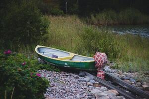 verlaten oud houten boot Aan een rivier- bank in de avond foto