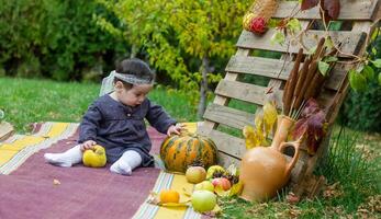 de weinig kind spelen in de park met fruit, weinig meisje in de herfst park foto