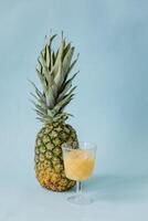 ananas sap in een glas met een ananas Aan een blauw achtergrond foto