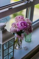 boeket van roze pioenen in een glas vaas Aan de vensterbank foto