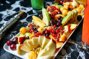 bord van fruit en glas van sap Aan tafel foto