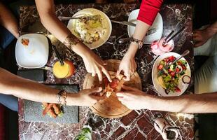 groep van mensen staand in de omgeving van een tafel met borden van voedsel foto