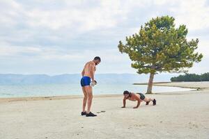jong gespierd Mens oefenen Aan de strand, jong gespierd Mens aan het doen lichaamsbouw opdrachten Aan de strand, atletisch jong Mens Aan de strand foto