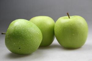 een stack van drie groen appels Aan wit achtergrond foto