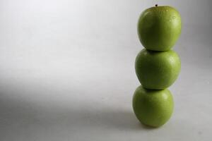 een stack van drie groen appels Aan wit achtergrond foto