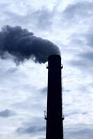 schoorsteen van industrieel fabriek besmetten lucht onder bewolkt hemels foto