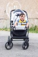 baby jongen in wandelwagen in de tuin foto