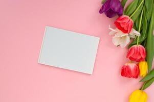 blanco wit kaart met kleurrijk tulpen Aan een roze achtergrond. foto