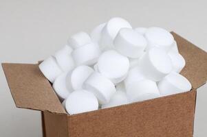 wit ronde vaatwasser zout tablets in een doos. een reeks van wit capsules in een Open doos top visie foto