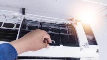 de concept van draag- uit onderhoud Aan de kamer lucht conditionering, een onderhoud technicus schoonmaak de filter Aan de binnen- lucht conditioning sectie, onderhoud werkwijze Aan de kamer lucht conditionering. foto