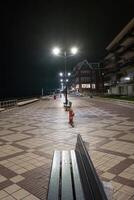 nacht schot van een promenade met bank en lantaarn foto