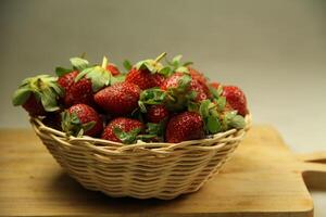 een mand van aardbeien Aan een houten besnoeiing bord Aan wit achtergrond foto