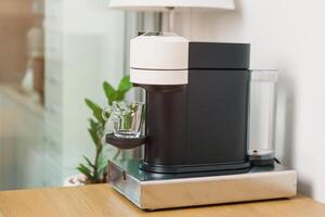 espresso koffie maker machine met capsule van geroosterd koffie Boon Aan hout tafel bar. dagelijks drank drinken Bij huis, appartement en kantoor concept foto
