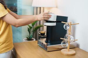 hand- maken espresso koffie door koffie maker machine met capsule van geroosterd koffie Boon Aan hout tafel bar. dagelijks drank drinken Bij huis, appartement en kantoor concept foto