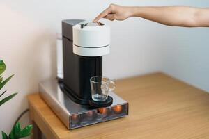 hand- maken espresso koffie door koffie maker machine met capsule van geroosterd koffie Boon Aan hout tafel bar. dagelijks drank drinken Bij huis, appartement en kantoor concept foto