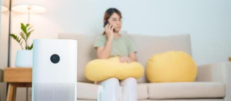 lucht luchtreiniger met vrouw kom tot rust en gebruik smartphone Aan bank. Zuivering systeem voor filter en schoonmaak stof pm2.5 hepa en virus in huis. allergie, zuiver lucht, Gezondheid, welzijn levensstijl en lucht verontreiniging foto