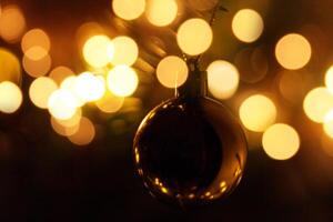 gouden bal Aan een Kerstmis boom met bokeh lichten Bij nacht. wijnoogst Kerstmis kaart foto