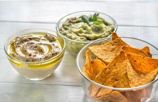 kommen van hummus en guacamole met tortilla chips foto