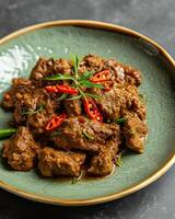 ai gegenereerd rendang met gesneden pepers Aan een licht groen bord Aan een grijs tafel achtergrond foto