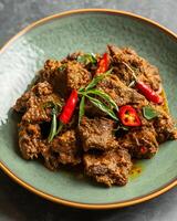 ai gegenereerd rendang met gesneden pepers Aan een licht groen bord Aan een grijs tafel achtergrond foto