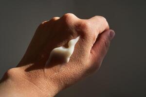 een smeren van wit vochtinbrengende crème of zonnescherm Aan een vrouw hand. foto