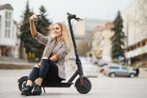 mooi jong vrouw zittend Aan haar elektro scooter . foto