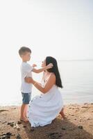 moeder en zoon wandelen Aan zonsondergang strand foto