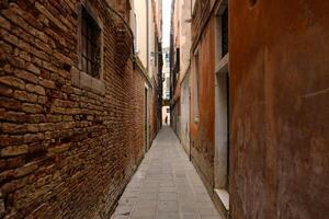 typisch versmallen straat met historisch huizen in Venetië. versmallen voetganger straten van Venetië tussen de kanalen. foto