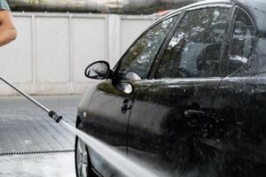 het wassen luxe zwart auto Aan contactloos auto wassen. schoonmaak de details van auto. het wassen sedan auto met schuim Zelfbediening en hoog druk water. netheid en bestellen in stedelijk milieu foto