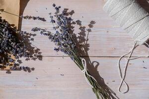 top visie vlak leggen van werkwijze maken boeketten van droog lavendel bloemen. katoen touw, schaar. vrouw Doen eigengemaakt kruiden boeket. voorbereidingen treffen voor winter foto