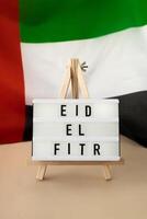 eid el fitr - eid mubarak - gelukkig vakantie tekst kader Aan Verenigde Arabisch emiraten golvend vlag gemaakt van zijde materiaal. openbaar vakantie viering achtergrond. de nationaal vlag van vae. patriottisme herdenking dag moslim Ramadan gezegend heilig maand concept foto
