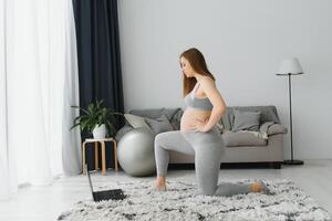 gezond zwangerschap yoga en geschiktheid concept. jong zwanger yoga vrouw werken uit in leven kamer interieur. foto