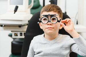 jong jongen ondergaan oog test met bril in medisch kliniek. foto