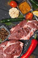 rauw varkensvlees vlees Aan houten snijdend bord Bij keuken tafel voor Koken varkensvlees steak geroosterd of gegrild met ingrediënten kruid en specerijen , vers varkensvlees. foto