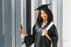 vrolijke Afro-Amerikaanse afgestudeerde student met diploma in haar hand foto