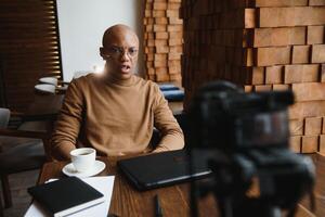 Afro-Amerikaans ondernemer vervelend overhemd met gerold omhoog mouwen op zoek door venster met attent en echt gezicht uitdrukking, gevoel nerveus voordat vergadering met bedrijf partners Bij cafe. foto