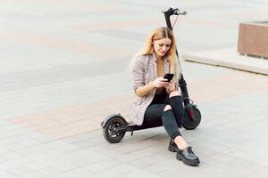 jong vrouw Aan elektro scooter in stad. vrouw rijden scooter in zonsondergang licht in straat foto