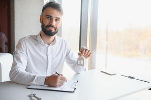 portret van een jong makelaar in de kantoor Bij de tafel. echt landgoed verkoop concept. foto