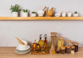 elegant keuken achtergrond met een reeks van flessen met divers Koken oliën, glas potten met specerijen. voorkant visie van een Open houten plank foto