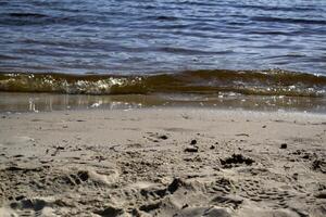 nat zand en zacht golven Aan een strand. foto