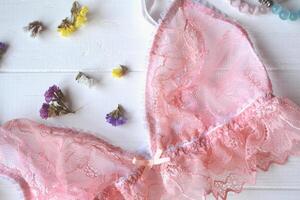 vrouw accessoires Aan de houten bureau. mooi kant lingerie, bloemen en nagel Pools. foto