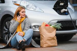 vrouw in de buurt een verhuur elektrisch auto. voertuig opgeladen Bij de opladen station. foto