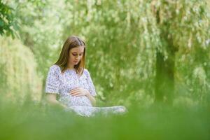 mooi zwanger vrouw ontspannende in de park foto