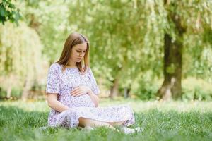 mooi zwanger vrouw ontspannende in de park foto