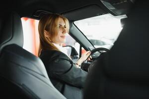 jong mooi vrouw tonen haar liefde naar een auto in een auto toonzaal. foto